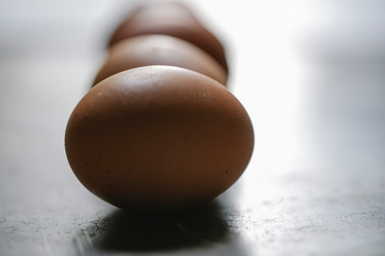 A close-up shot of brown eggs lined up on a surface with a blurred background.